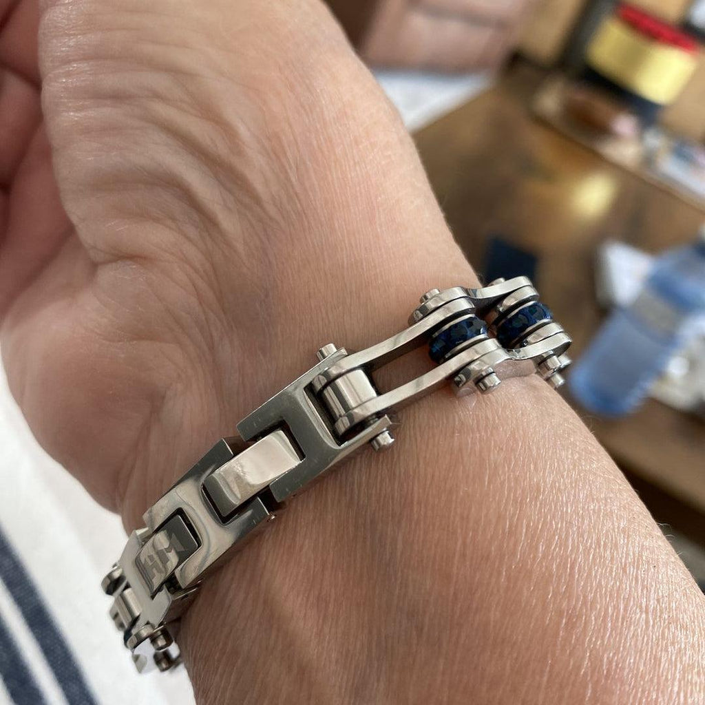 Close-up of a hand wearing a silver bracelet with a blurred background